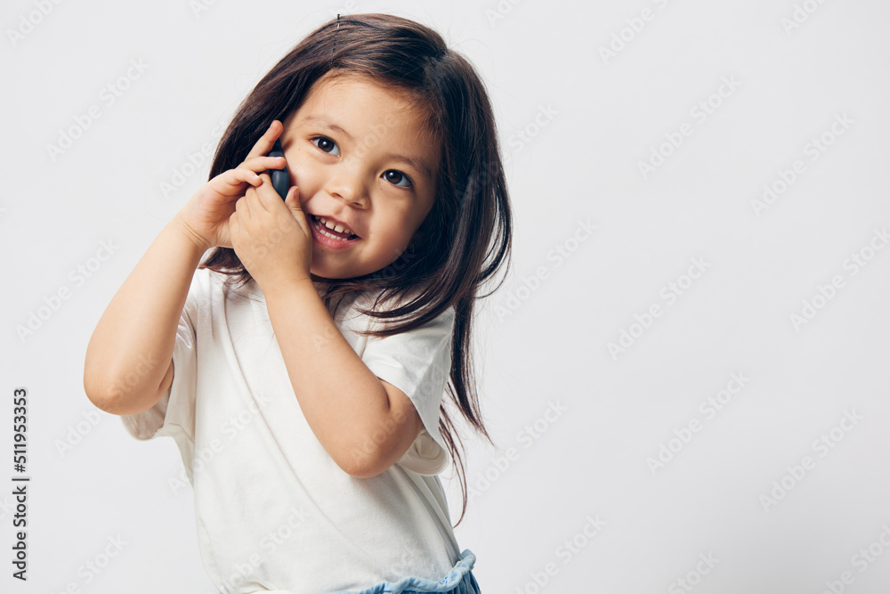 close portrait of a happy, joyful little girl talking on a trendy smartphone while holding it with both hands close portrait of a happy, joyful little girl talking on a trendy smartphone while holding it with both hands