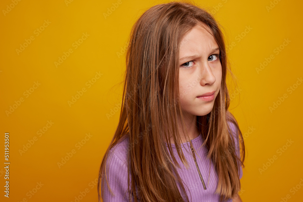 Portrait of a young girl with an angry expression, on a clean yellow background, space for text Portrait of a young girl with an angry expression, on a clean yellow background, space for text