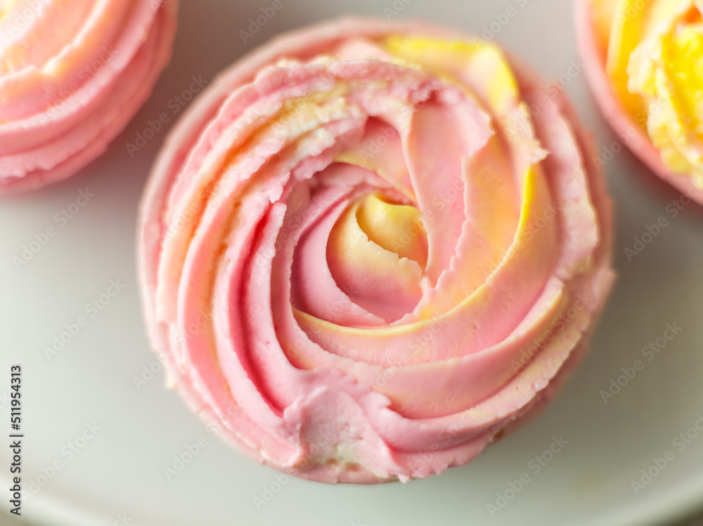 Closeup top view of handmade cupcake with pink yellow cream made as rose flower. Sweet pastry background