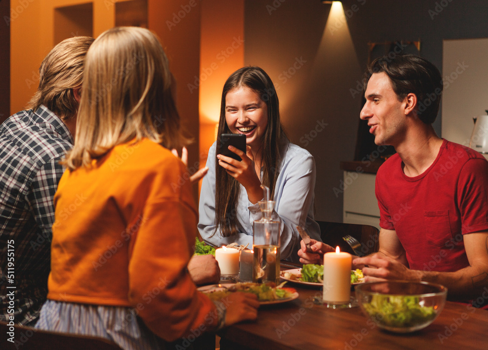 © Comeback Images - Woman laughing joyfully while reading message on cell phone or showing funny pictures to friends at dinner © Comeback Images - Woman laughing joyfully while reading message on cell phone or showing funny pictures to friends at dinner