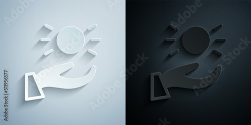 Paper cut Ball levitating above hand icon isolated on grey and black background. Levitation symbol. Paper art style. Vector