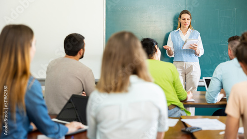 Female teacher giving lecture to university students in classroom.
