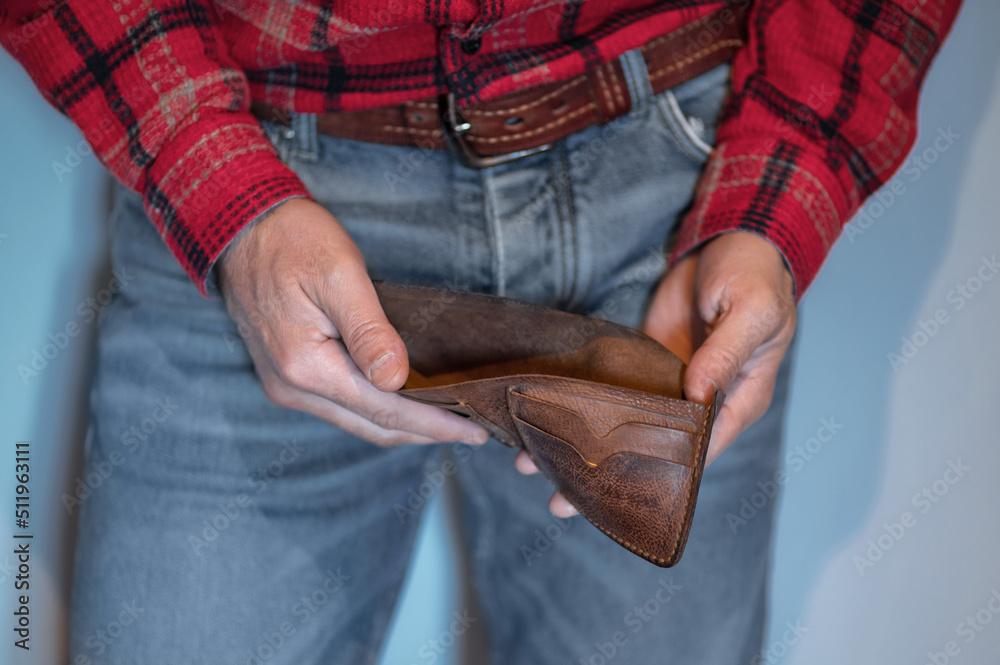 Fototapeta premium A man opens an empty wallet in close-up.