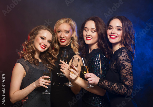Group of partying women clinking flutes with sparkling wine over blue background