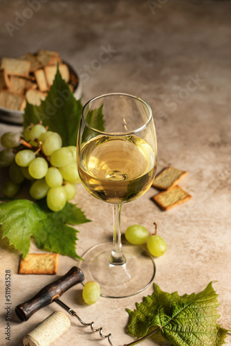 White wine glass on brown textured background with corkscrew and grapes and crackers. Text space