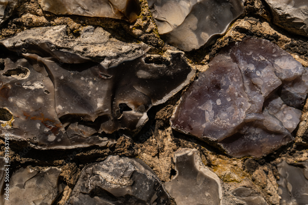 Closeup on various flint stones used in UK as a building material in architecture. Flint is the hardest of building stones, used by the Romans for castle walls and by medieval masons for churches Closeup on various flint stones used in UK as a building material in architecture. Flint is the hardest of building stones, used by the Romans for castle walls and by medieval masons for churches