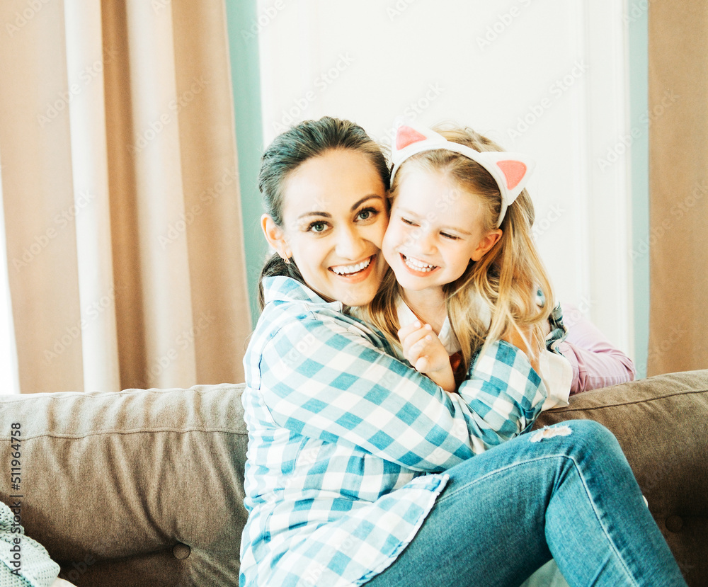 Loving young mother laughing hugging smiling cute cheerful daughter
