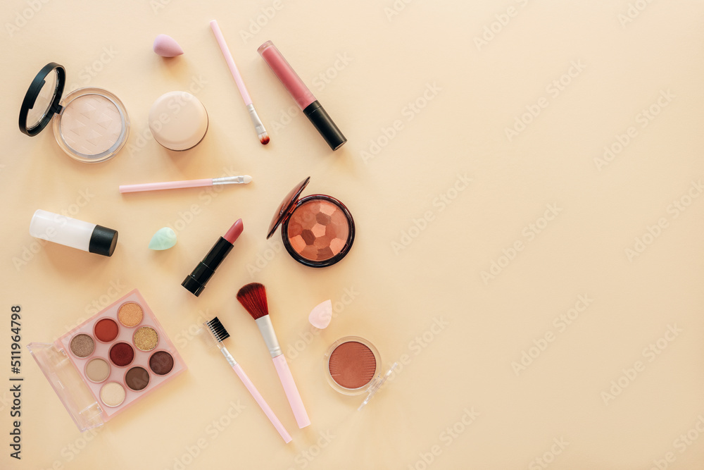 Flat lay makeup with skin foundation, lipstick, eye shadow palette, powder and beauty accessories. Cosmetic beauty products on a pastel beige background. Top view, copy space Flat lay makeup with skin foundation, lipstick, eye shadow palette, powder and beauty accessories. Cosmetic beauty products on a pastel beige background. Top view, copy space