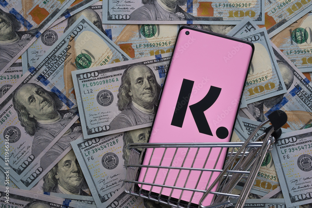 Klarna app logo seen on the screen of smartphone placed on dollar bills