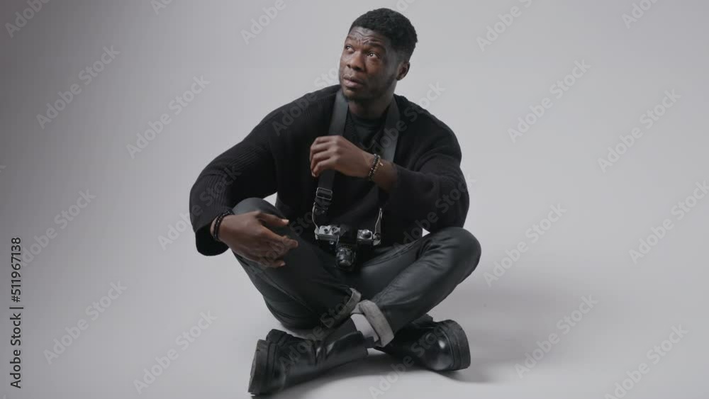 Attractive Afro-American man keeps camera on his neck, then looks up full shot grey background isolated copy space . High quality 4k footage Attractive Afro-American man keeps camera on his neck, then looks up full shot grey background isolated copy space . High quality 4k footage