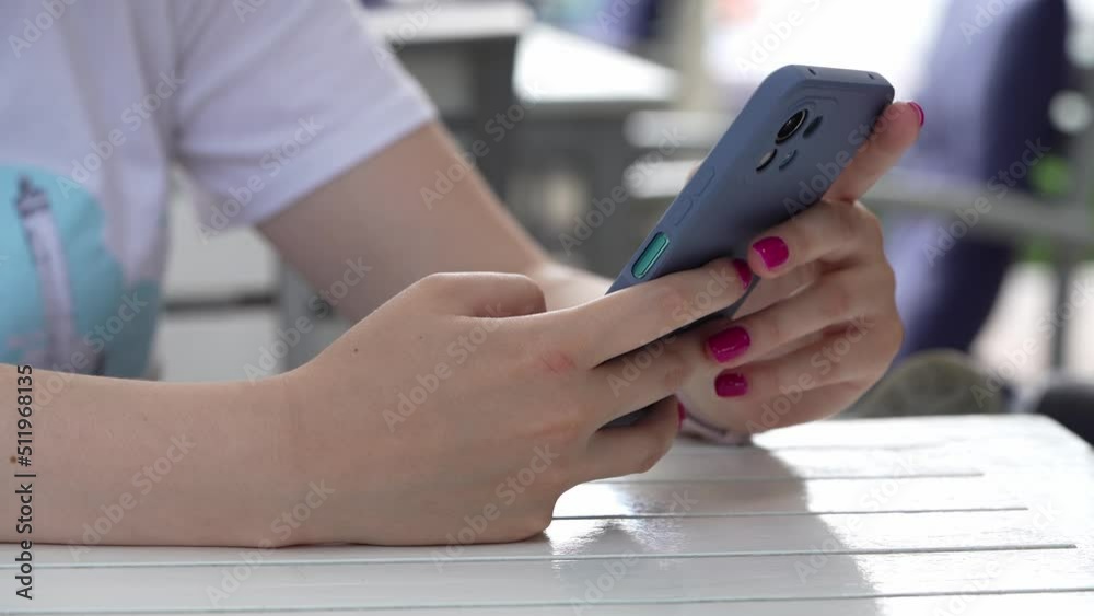 Close up on hands of unknown caucasian woman using mobile phone for texting and communication browsing internet or social network in day sitting outdoor Close up on hands of unknown caucasian woman using mobile phone for texting and communication browsing internet or social network in day sitting outdoor