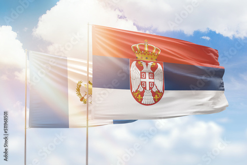 Sunny blue sky and flags of serbia and guatemala photo