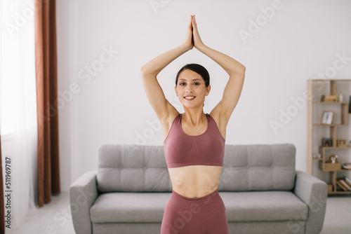 Attractive and healthy young woman doing yoga exercises while resting at home