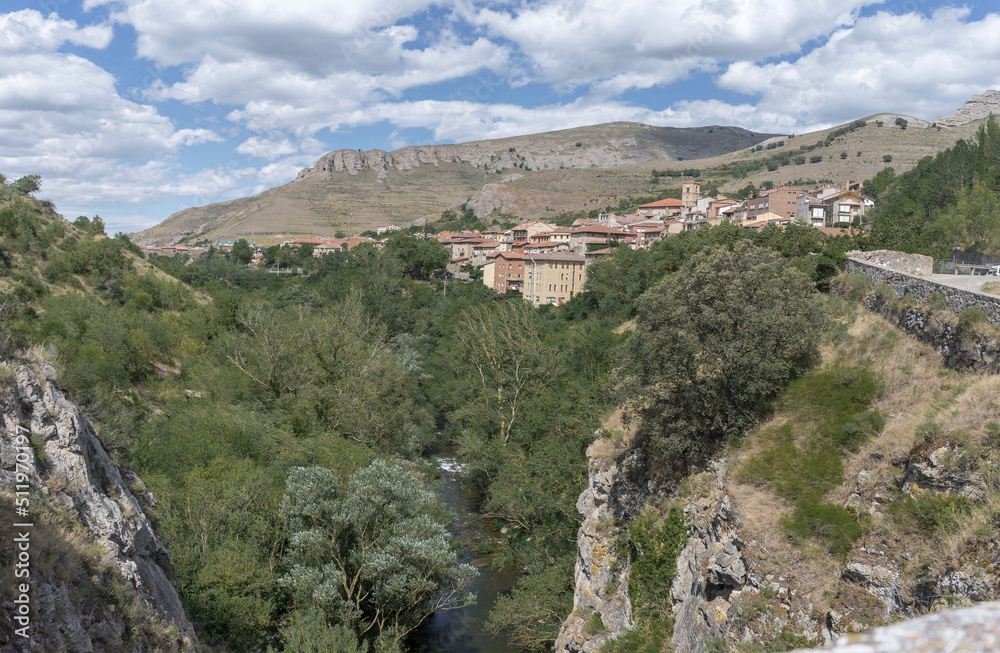 Beautiful views of the village of Anguiano surrounded by mountains and lots of vegetation with a blue summer sky, Spain.