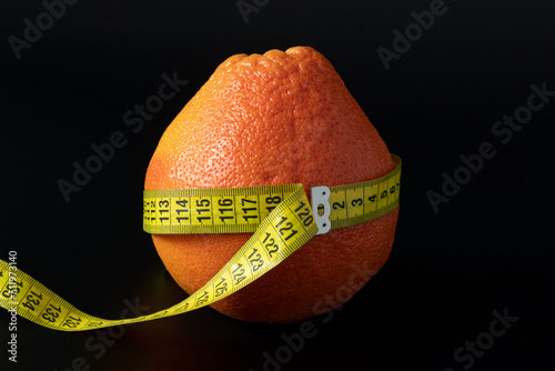 Bilde på lerret Fresh orange wrapped with measuring tape on a black background