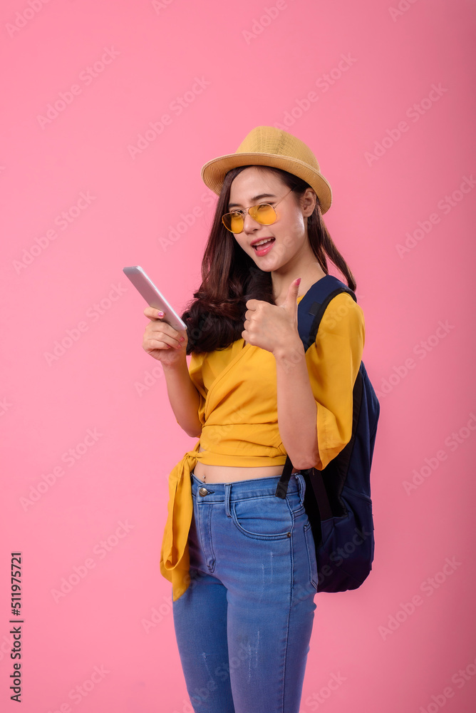 Happy traveler Asian woman joy relaxing on summer vacation holding smartphone with small backpack on pink background. Happy traveler Asian woman joy relaxing on summer vacation holding smartphone with small backpack on pink background.
