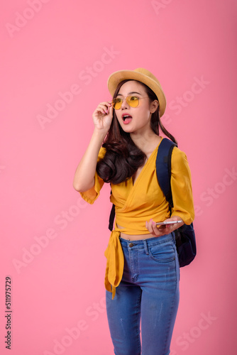 Happy traveler Asian woman joy relaxing on summer vacation holding smartphone with small backpack on pink background.