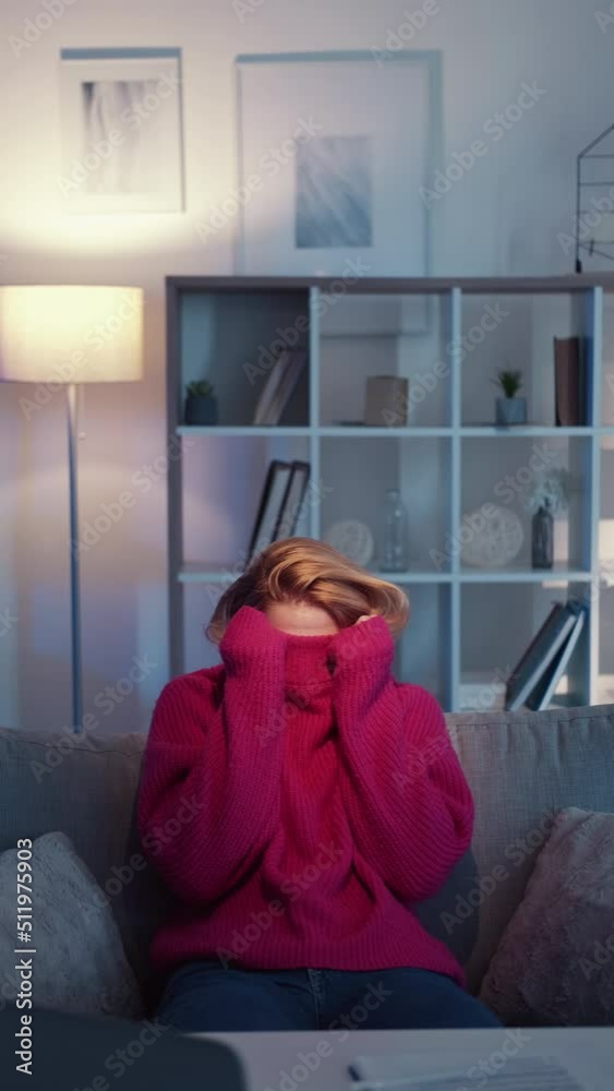 Hiding woman. Silly situation. Meme expression. Unrecognizable lady pulling sweater over head sitting work desk in light room interior looped vertical.