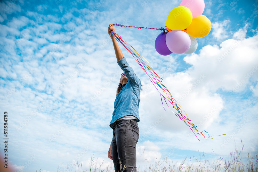 Woman holding balloons running on green meadow white cloud and blue sky with happiness Cheerful and relax. Hands holding vibrant air balloons play on birthday party happy times summer sunlight outdoor Woman holding balloons running on green meadow white cloud and blue sky with happiness Cheerful and relax. Hands holding vibrant air balloons play on birthday party happy times summer sunlight outdoor