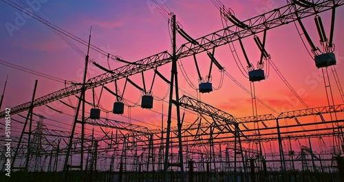 Aerial footage of high voltage power tower in substation. Transmission power line. Electricity pylons and sky clouds background at sunset.