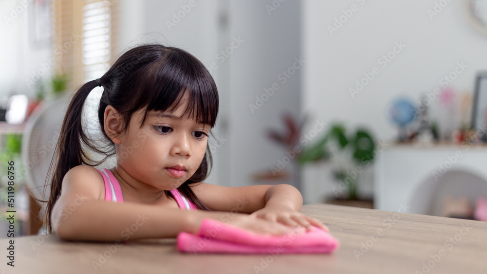happy little Asian girl learning to clean with a rag in the living room at home. housework and household concept. happy little Asian girl learning to clean with a rag in the living room at home. housework and household concept.