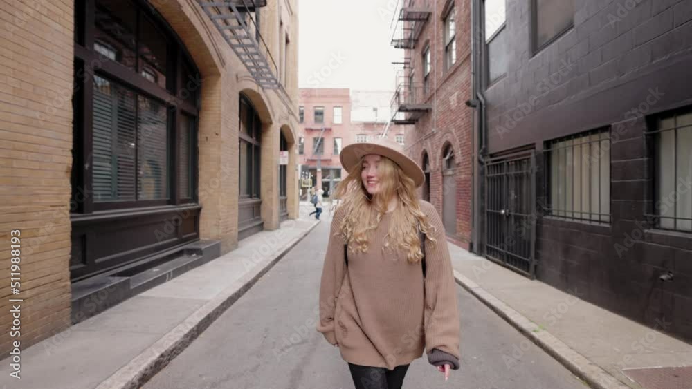 Woman enjoying vistas of beautiful urban architecture with brick facades. Smiling, cheerful backpacker traveling around downtown in a big city. High quality 4k footage Woman enjoying vistas of beautiful urban architecture with brick facades. Smiling, cheerful backpacker traveling around downtown in a big city. High quality 4k footage