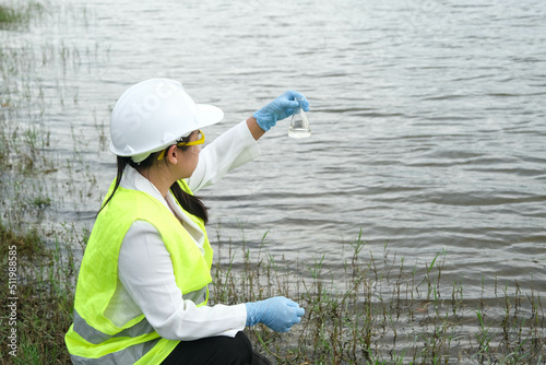 Female environmentalist in a glove takes a sample of lake water to survey and test for infection. Female researcher surveys contaminants in natural water bodies. Water and ecology concept.