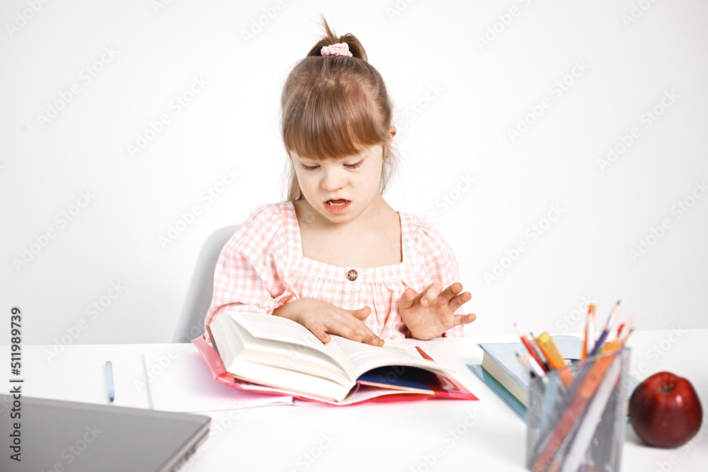 Girl with Down syndrome studying while sitting at desk at home Girl with Down syndrome studying while sitting at desk at home