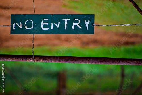 No Entry Sign on a wooden fence with old rusted gate