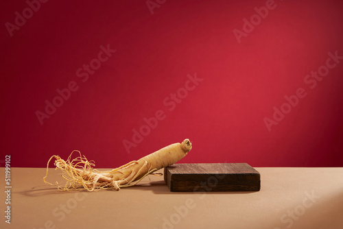 Fotografie Front view of ginseng in wooden tray and red background