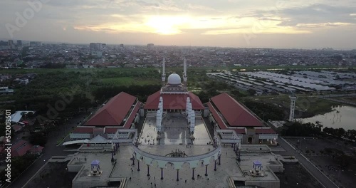 Reveal drone shot of the great Mosque of Central Java (MAJT) in suset time. Th sun is orange and the weather is cloudy. photo