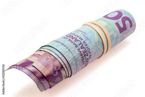 Roll of New Zealand banknotes secured by a rubber band and isolated against a white background.