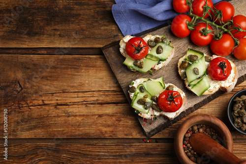 Bruschettas with capers, vegetables and cream cheese served on wooden table, flat lay. Space for text