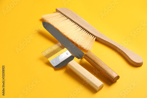 Three different beekeeping tools on yellow background