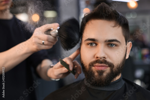 Professional hairdresser working with client in barbershop