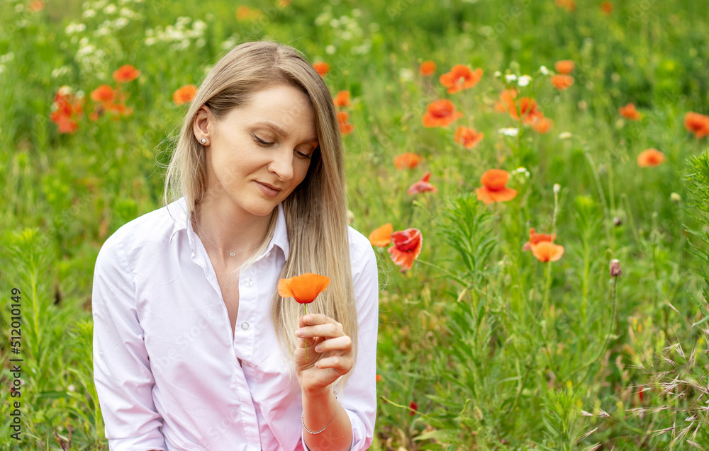 portrait of young beautiful blonde hair woman sitting in poppy flowers field.pretty girl with poopy by ear or in hand.green nature,cloudy sky,summer time. portrait of young beautiful blonde hair woman sitting in poppy flowers field.pretty girl with poopy by ear or in hand.green nature,cloudy sky,summer time.