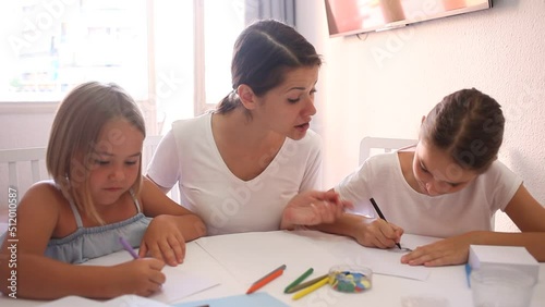 Portrait of happy mother with two daughters draw at table at home  photo