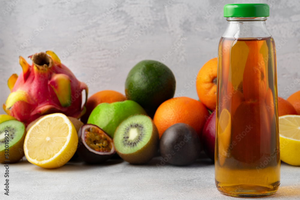 Various fruits and freshly squeezed fruits juice in bottle on gray background Various fruits and freshly squeezed fruits juice in bottle on gray background
