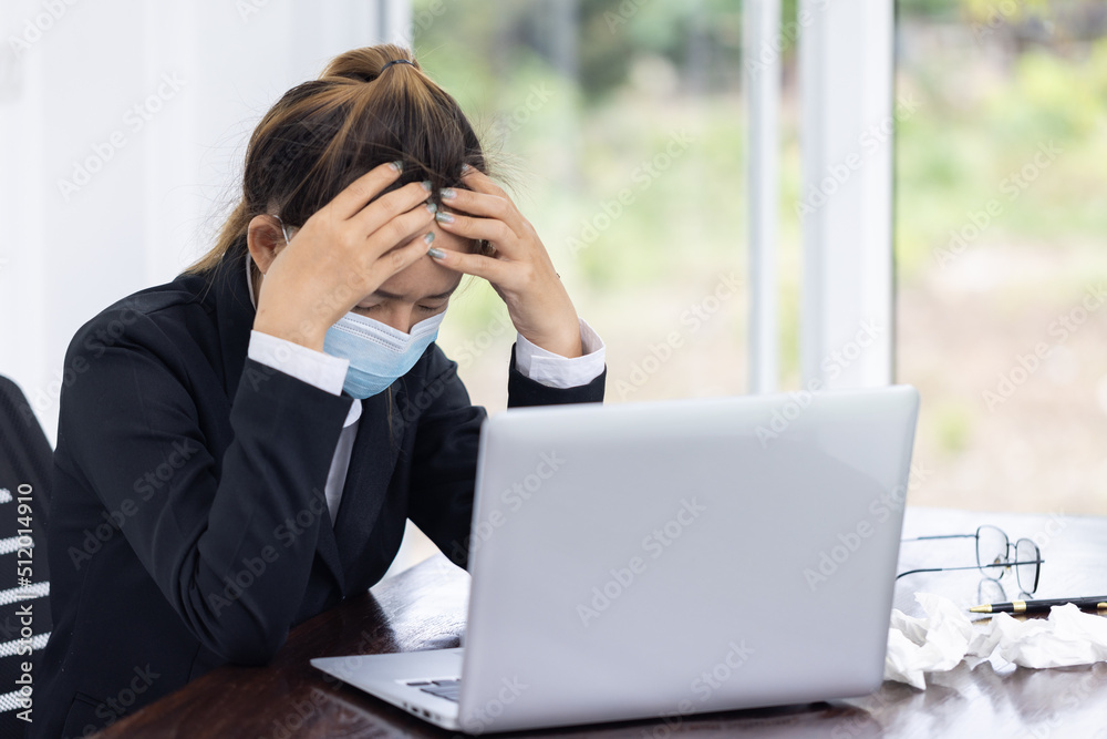 Female employee wearing a medical mask while working alone, Sickness while working. Female employee wearing a medical mask while working alone, Sickness while working.