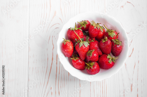 strawberries lie in a plate on a white wooden background
