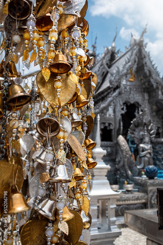 Ofrendas en templo budista tailandes. Campanillas doradas y plateadas, en templo Srisuphan