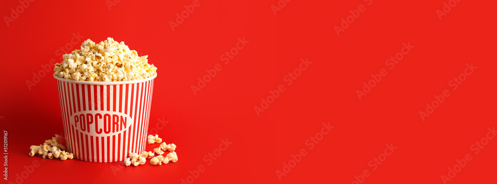 Bucket with tasty popcorn on red background with space for text