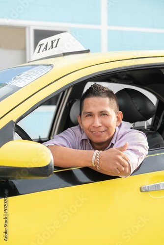 Ecuadorian taxi driver inside a yellow taxi. Latin man looking at camera. Copyspace.