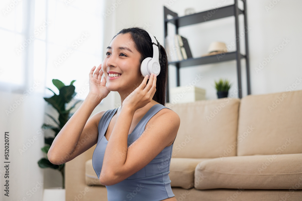 Beautiful asian woman in sportswear put on headphone listening music relax after workout. Cheerfully sporty female workout and exercise wearing sport wear at home. Beautiful asian woman in sportswear put on headphone listening music relax after workout. Cheerfully sporty female workout and exercise wearing sport wear at home.