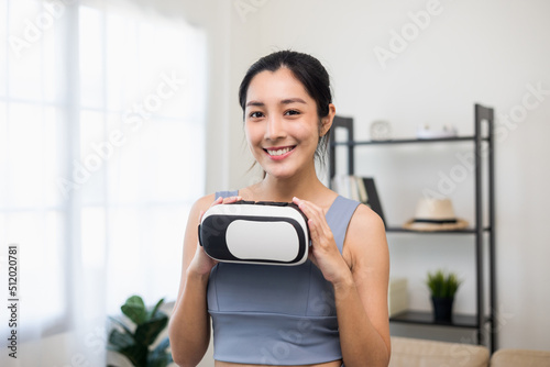 Young asian sport woman holding vr glasses wearing sportswear workout with virtual simulated world. Into the  future digital cyber universe. Future technology Training virtual sport at home