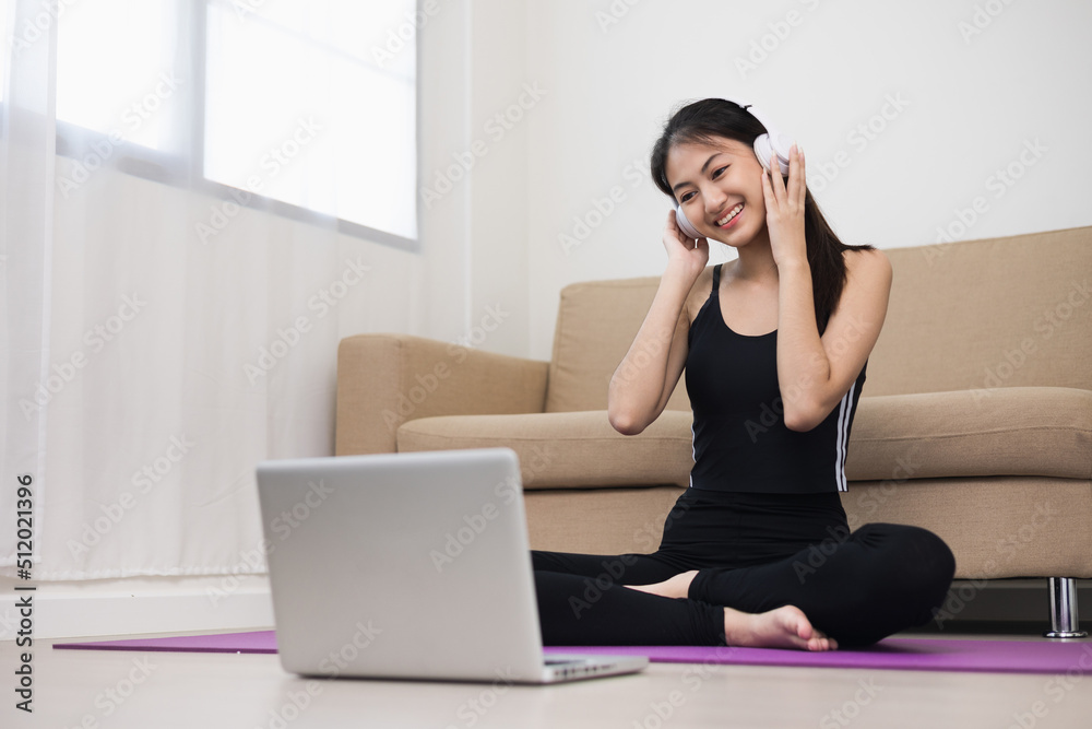Young asian sport woman sitting practicing yoga lesson. Stretching leg training workout at home for good health and body shape. Learning skill form video online class by laptop. Young asian sport woman sitting practicing yoga lesson. Stretching leg training workout at home for good health and body shape. Learning skill form video online class by laptop.