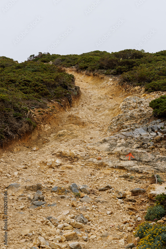 Obraz premium A subtle trail marker shows the way up a hilly incline on a hiking trail in Portugal