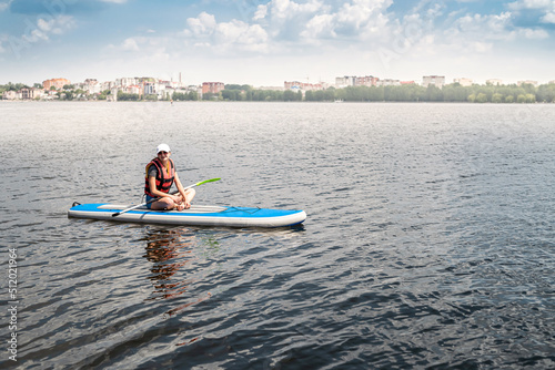 an experienced athlete in a vest rides on the water on a board sap on the lake in weather.