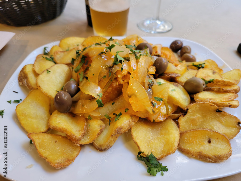 A plate of fried potatoes and bacalau fish with a beer A plate of fried potatoes and bacalau fish with a beer