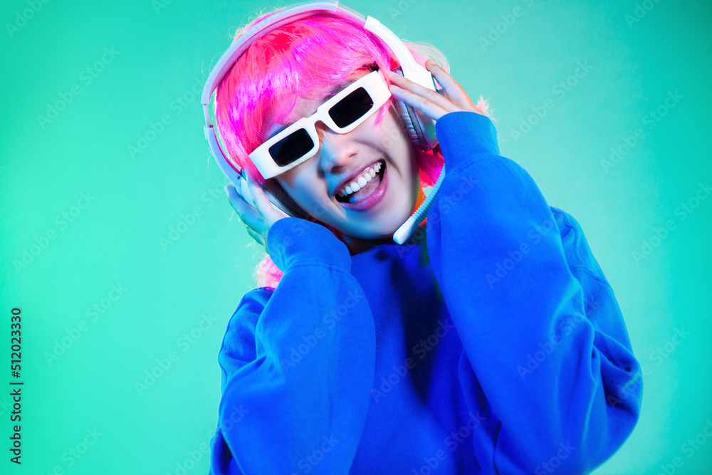 Young asian girl pink color hair punk style in blue sweatshirt wearing sunglasses and headphone on green screen background. Young asian girl pink color hair punk style in blue sweatshirt wearing sunglasses and headphone on green screen background.